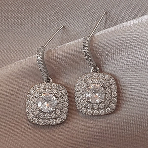 Macro shot of silver square halo earrings featuring double-row pavé-set clear zircons