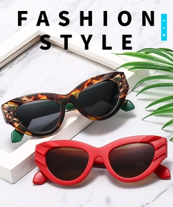 Detail of cat-eye sunglasses featuring textured carving on tortoiseshell and red frames
