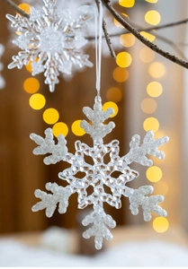 Close-up of transparent acrylic snowflake pendant with glitter on a Christmas tree