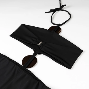 Detail of black halter bikini featuring glossy brown circular accents and metal rings