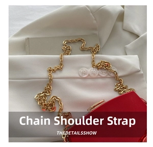 Detailed close-up of thick gold chain strap on chic red hardshell evening clutch bag