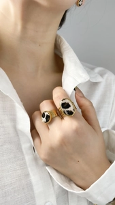 Detail view of gold leopard print open ring and earring set on model with white shirt
