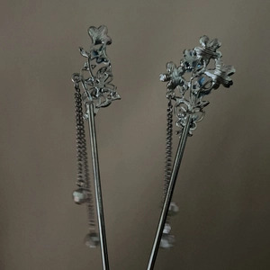 Close-up of butterfly and flower hair sticks with silver metal tassels in vintage style