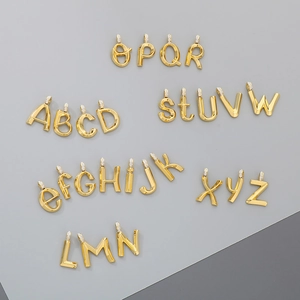 Macro shot of 26 gold stainless steel alphabet pendants with sparkling diamond accents