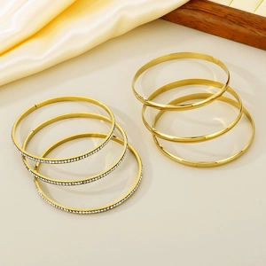 Detail of 6-piece gold titanium steel bangle set with minimalist and pavé crystal bands