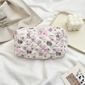 Detail of quilted white makeup bag with cartoon puppy print and pink heart pattern