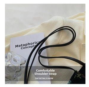Detail of a black embroidered tote bag strap with neat stitching on a minimalist background