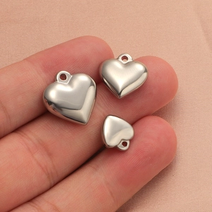 Detailed view of three polished stainless steel heart pendants in different sizes