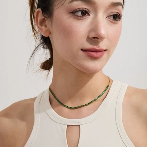Detail of 18k gold plated tennis necklace with green zircon stones on a female model