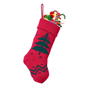 Macro shot of red knitted Christmas stocking with green tree pattern and small gifts