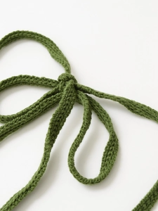 Macro detail of high-quality green hand-knitted fabric straps and crochet texture