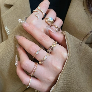 Detail of model wearing gold ring set with pink heart zircons and snake pattern rings