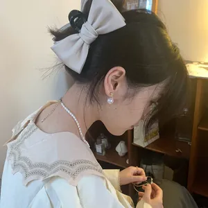 Elegant large cream satin bow hair claw clip styled on a woman with retro lace shirt