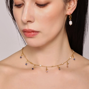 Close-up of gold necklace with lapis lazuli pendants and pearl earrings on a model