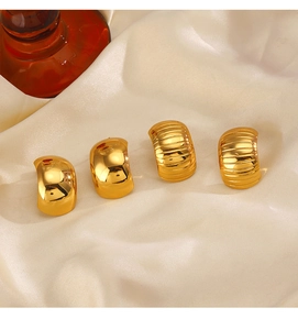 Close-up of gold C-shaped hoop earrings with textured finish on beige silk fabric