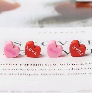 Macro detail of heart-shaped clay beads with LOVE engraving for DIY jewelry making