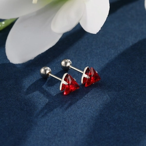 Detail view of red triangle gemstone stud earrings with screw back on navy textured fabric