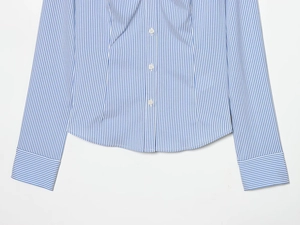 Detail view of the curved hem and blue vertical stripes on a slim-fit women's shirt