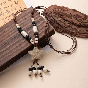 Detail of bohemian starfish pendant with ceramic texture and colorful beads on woven cord