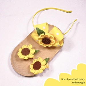 Detail of sunflower hair clip set with non-slip fabric padding and yellow bow design