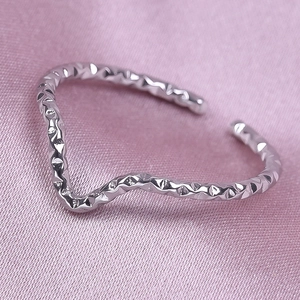 Macro detail of silver V-shaped wavy ring with hammered texture on pink silk fabric
