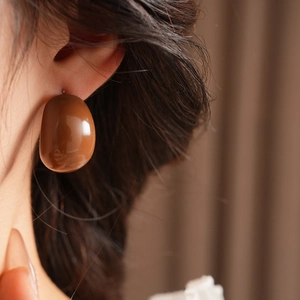 Detail view of a vintage C-shaped resin drop earring in brown worn by a model