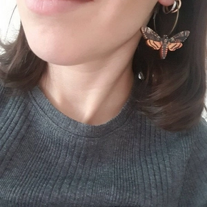 Gothic moth acrylic earrings featuring brown and orange patterns on female model
