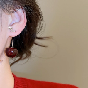 Primo piano di orecchini a ciliegia in resina vintage con foglie d'argento su modella
