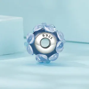 S925 sterling silver charm bead with blue glass flower design on light blue background