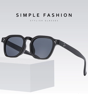 Detail view of black square sunglasses with silver three-dot rivets on geometric blocks