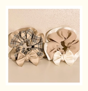 Detail of plaid and waffle fabric scrunchies with satin bows in neutral tones