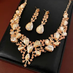 Luxury champagne crystal necklace and teardrop earrings set on a black leather display