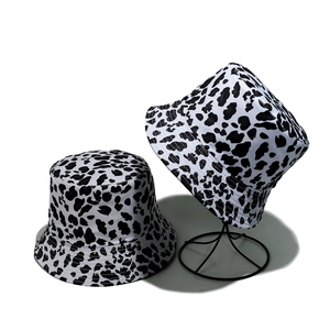 Detailed view of black and white cow print bucket hats on a professional display stand