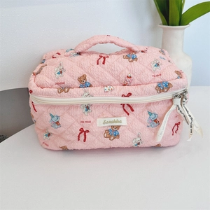 Pink quilted makeup bag with handle featuring cute cartoon bears and rabbits print