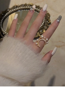 Detail of moon-shaped gold ring featuring white pearls and micro-pave cubic zirconia crystals
