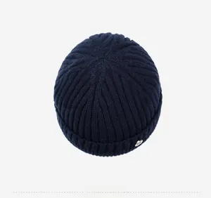 Detailed top view of navy blue knitted beanie with vertical stripes and metal tag