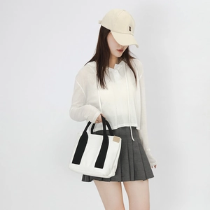 Minimalist canvas tote bag with black handles held by model in a high-quality lifestyle shot