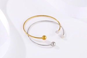 Détail de bracelets en C dorés et argentés avec strass sur fond de soie blanche