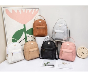 Detalle de mini mochilas con acolchado en V y adornos metálicos de mariposas elegantes