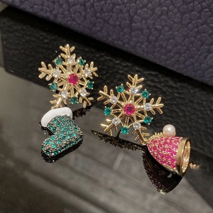 Detailed macro view of asymmetric Christmas earrings with colorful crystals on a black surface