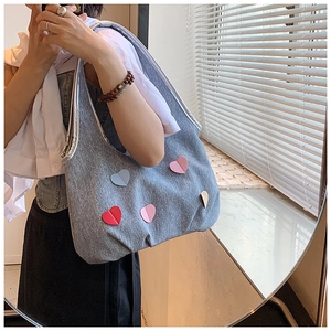 Détail d'un sac seau en toile grise avec écussons cœurs colorés et bordure argentée