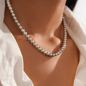 Close-up of silver beaded necklace on model's neck with polished metallic spheres