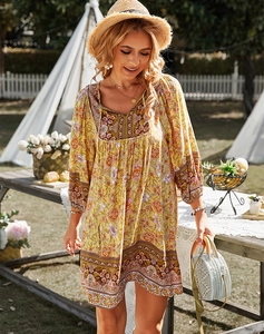 Détail d'une robe bohème jaune fleurie avec col en V et bordure cachemire dans un jardin