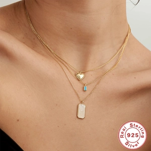 Close-up of triple-layered S925 silver necklace with turquoise and heart pendants