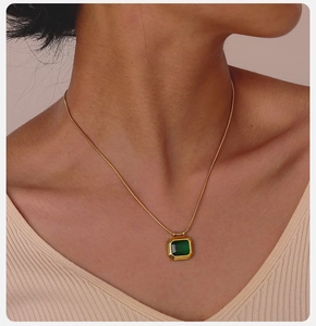 Detailed view of emerald-cut green stone pendant necklace on model neck and collarbone