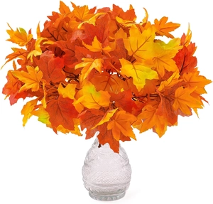 Artificial maple leaves in an embossed glass vase for autumn home table centerpiece