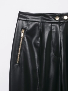 Detaillierte Makroansicht der schwarzen Kunstlederhose mit goldenem Reißverschluss und Schnalle