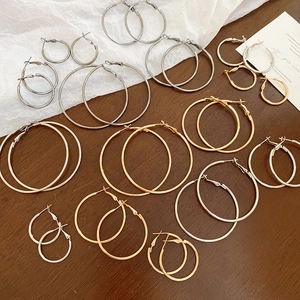 Close-up of assorted gold and silver metal hoop earrings in various sizes on a dark table