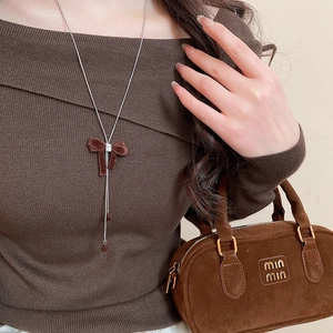 Detail of silver chain necklace with brown velvet bow and sparkling zircon stone on model