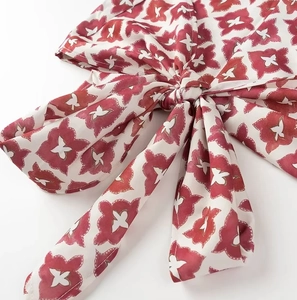 Close-up detail of red and white floral print with an elegant chiffon bow tie knot